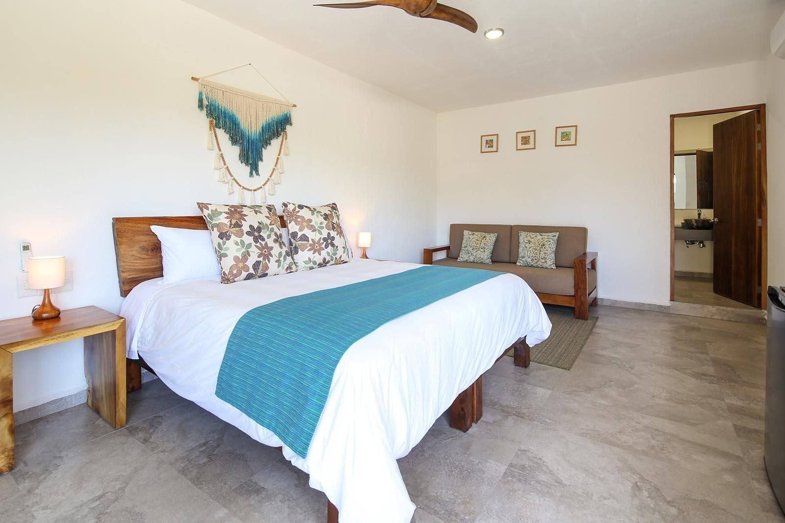 Casa Di Giulio: room with nightstands, a sofa, macramé wall hanging and framed prints